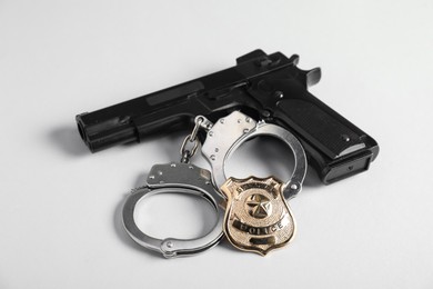 Photo of Police badge, gun and handcuffs on white background, closeup