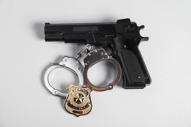 Photo of Police badge, gun and handcuffs on white background, above view
