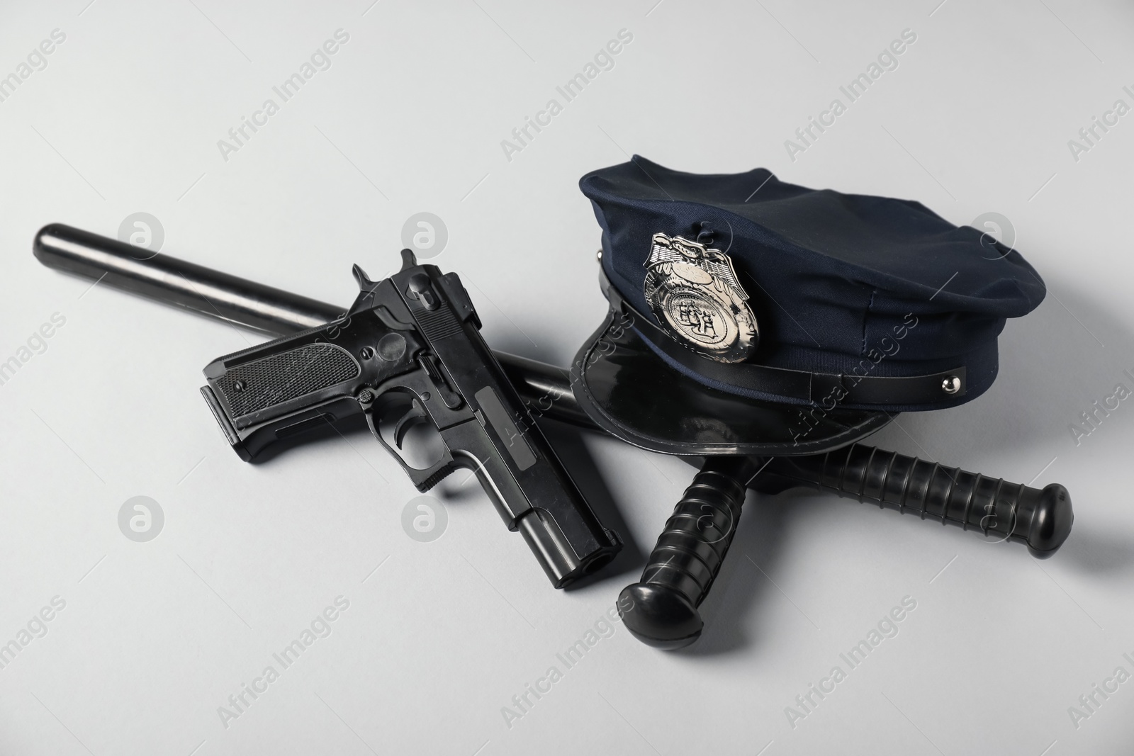Police cap, gun and baton on white background Photo of Police cap, gun and baton on white background