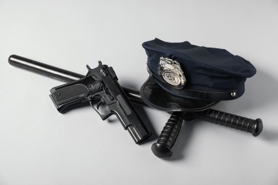 Photo of Police cap, gun and baton on white background
