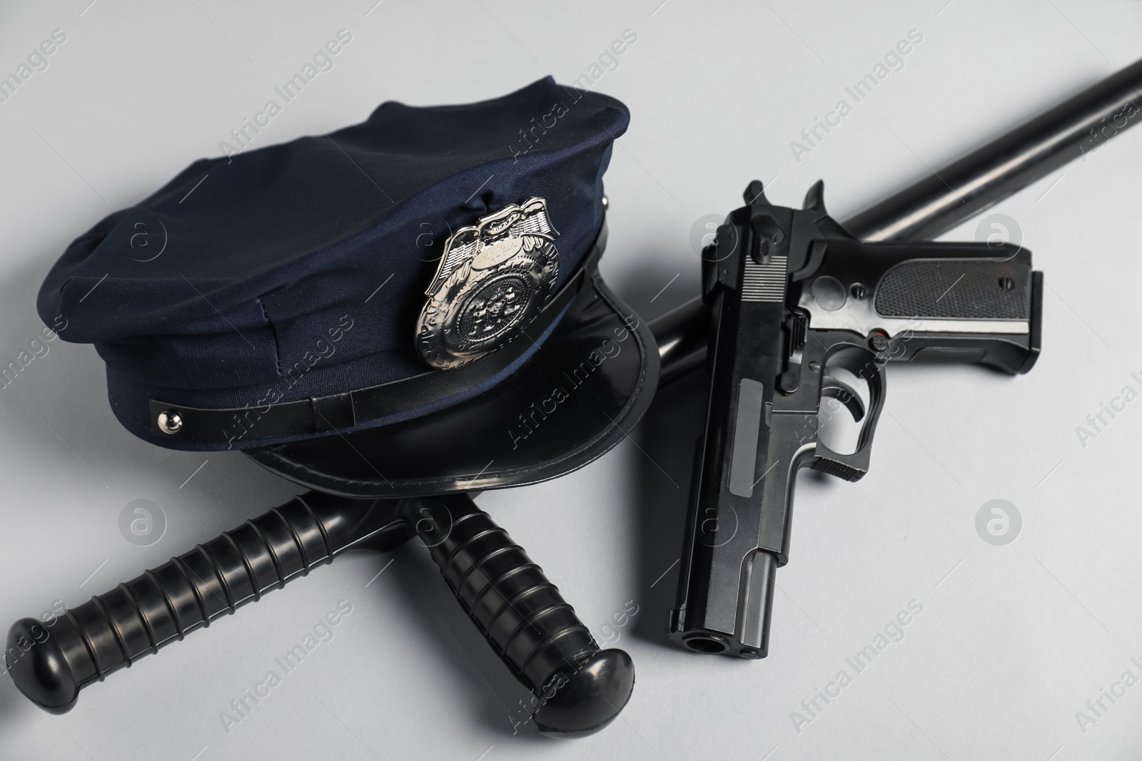 Police cap, gun and baton on white background, closeup Photo of Police cap, gun and baton on white background, closeup