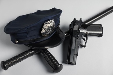 Photo of Police cap, gun and baton on white background, closeup