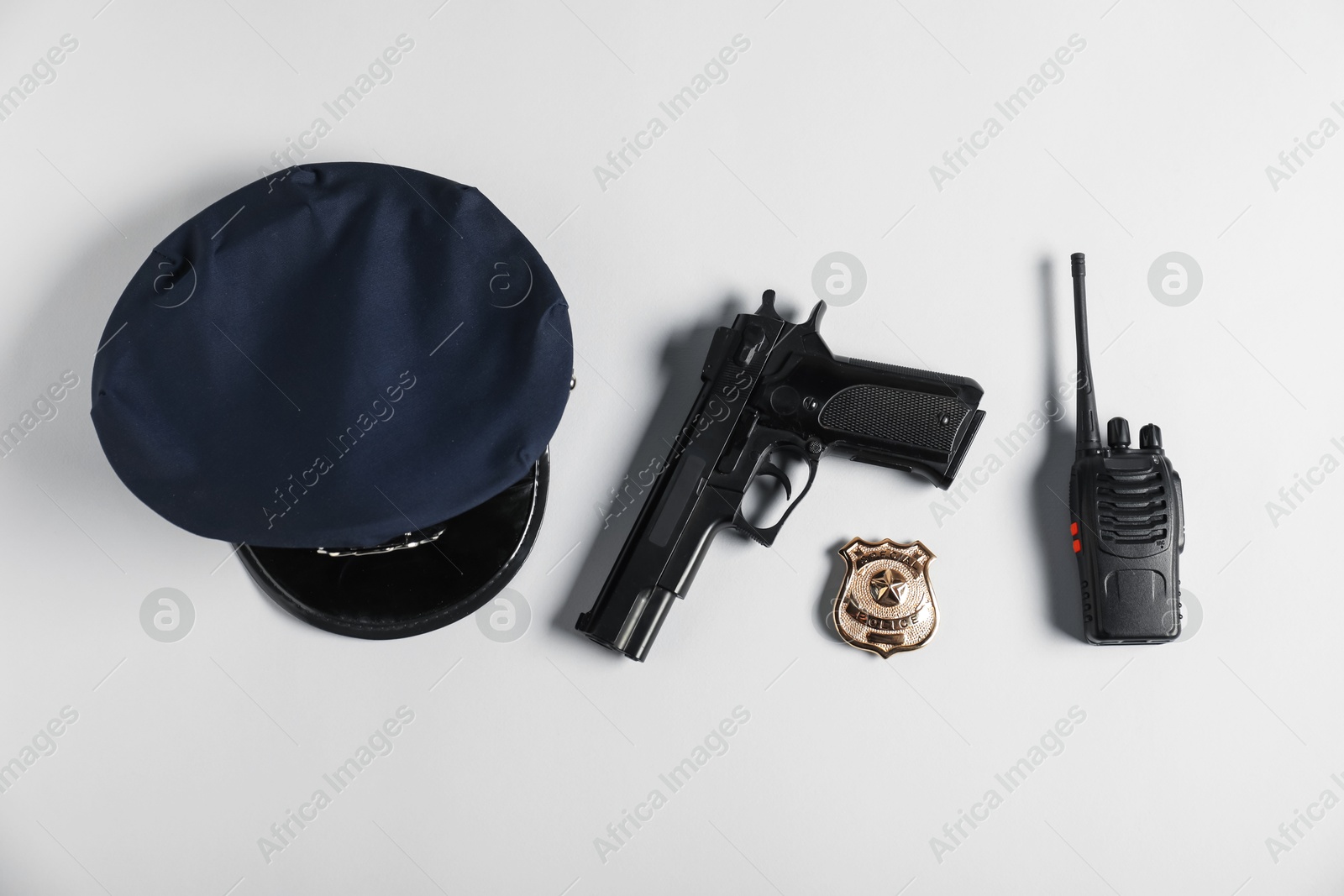 Police cap, gun, badge and walkie talkie on white background, flat lay Photo of Police cap, gun, badge and walkie talkie on white background, flat lay