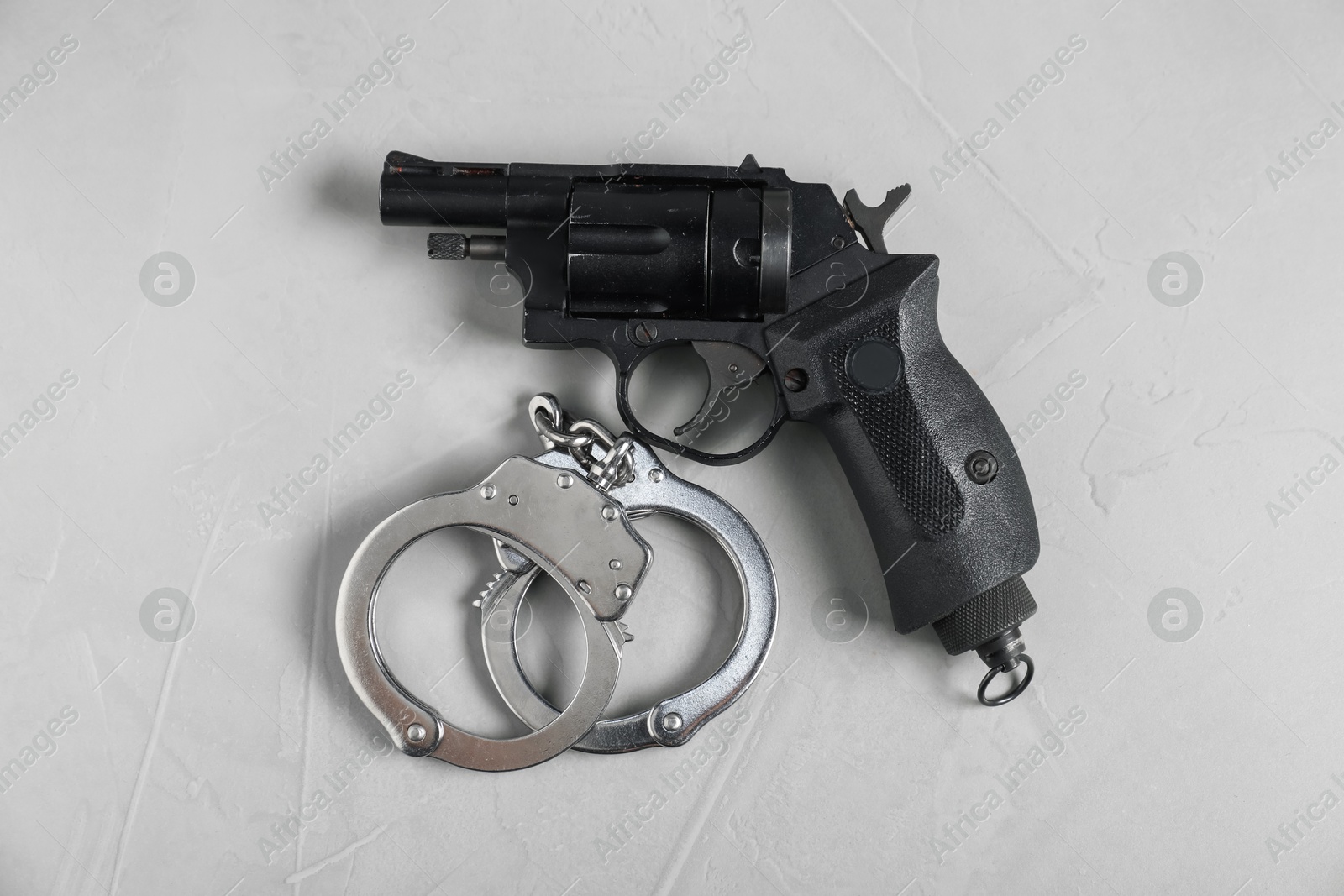 Gun and handcuffs on light grey table, flat lay Photo of Gun and handcuffs on light grey table, flat lay