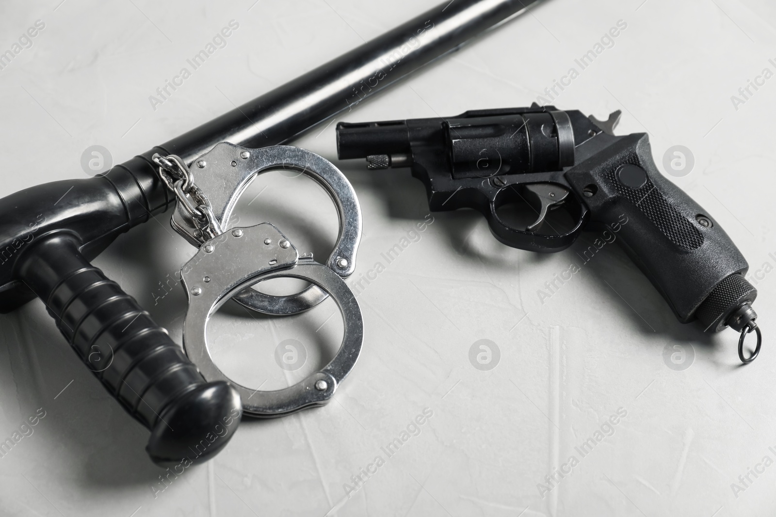 Police baton, handcuffs and gun on light grey table, closeup Photo of Police baton, handcuffs and gun on light grey table, closeup