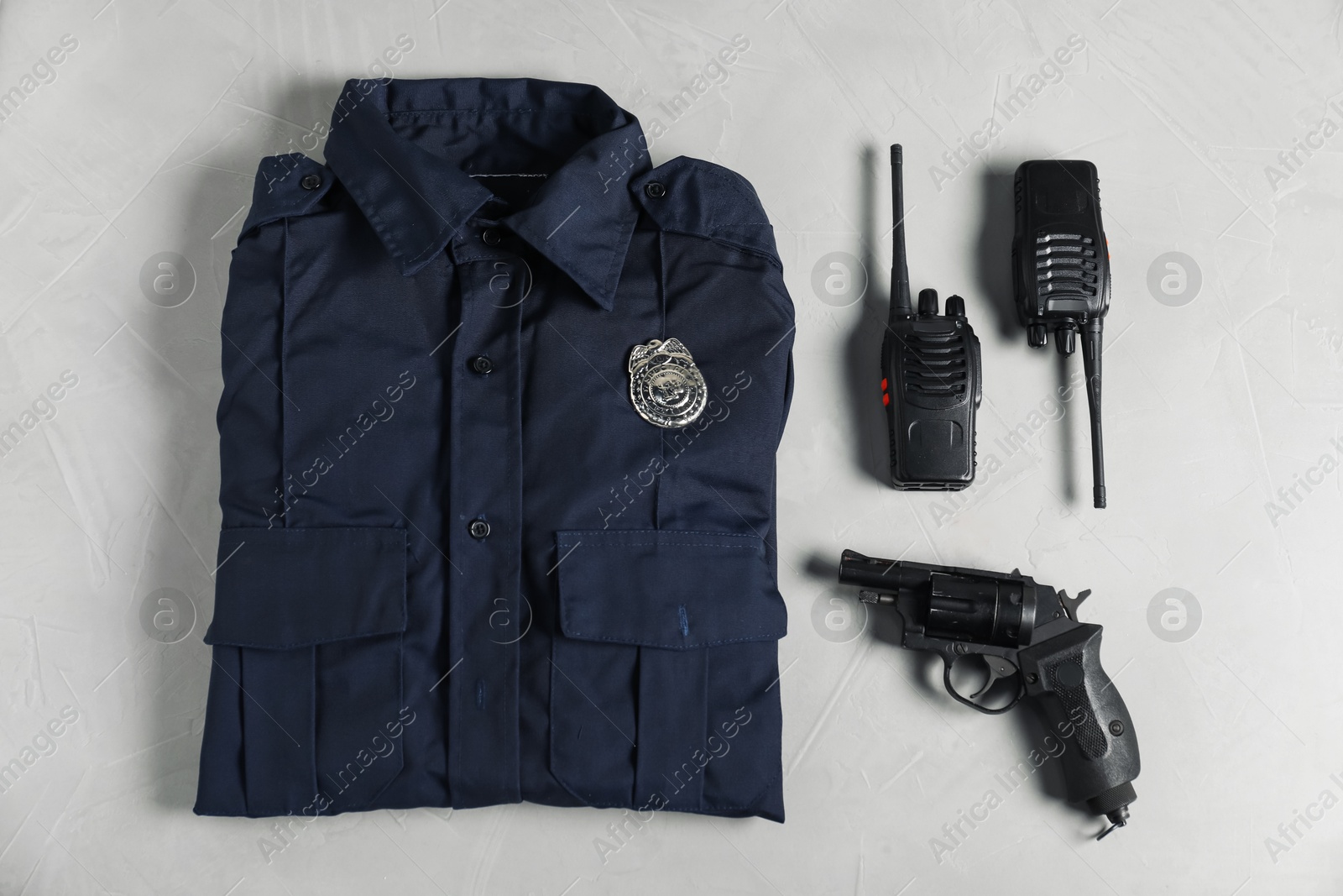 Photo of Police uniform, walkie talkies and gun on light grey table, flat lay