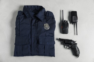 Photo of Police uniform, walkie talkies and gun on light grey table, flat lay
