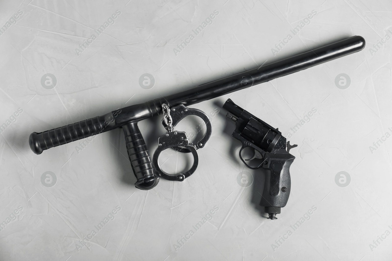 Police baton, gun and handcuffs on light grey table, flat lay Photo of Police baton, gun and handcuffs on light grey table, flat lay