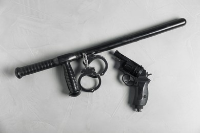 Photo of Police baton, gun and handcuffs on light grey table, flat lay