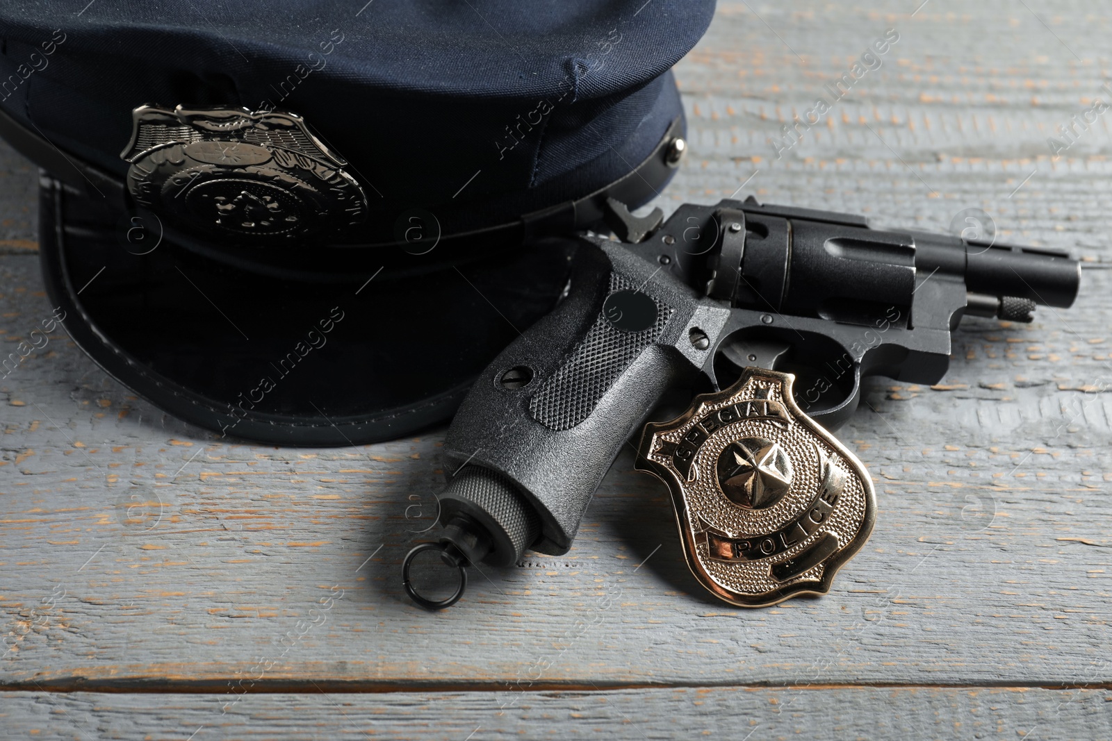 Police cap, gun and badge on grey wooden table, closeup Photo of Police cap, gun and badge on grey wooden table, closeup