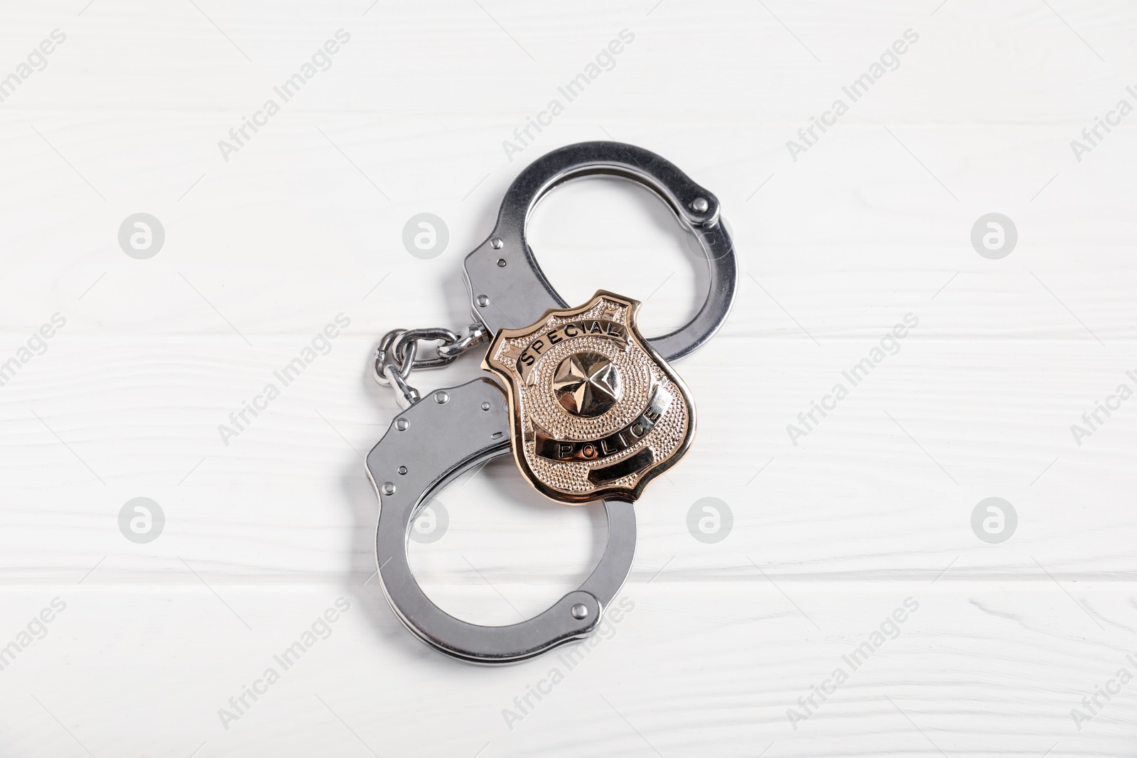 Police badge and handcuffs on white wooden table, top view Photo of Police badge and handcuffs on white wooden table, top view
