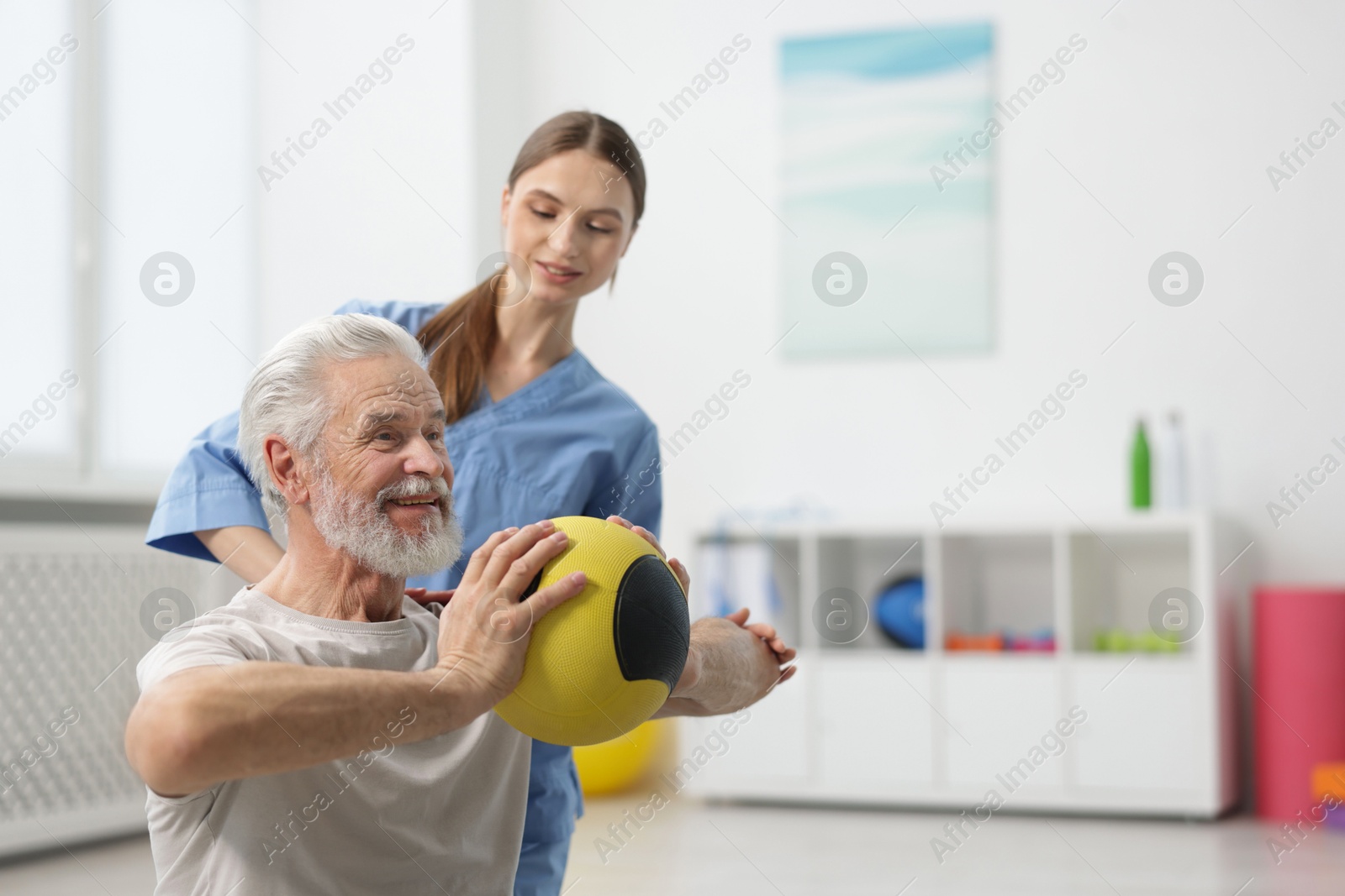 Doctor and patient exercising with medicine ball in clinic, space for text Photo of Doctor and patient exercising with medicine ball in clinic, space for text