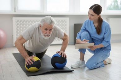 Photo of Doctor and patient exercising with medicine ball in clinic