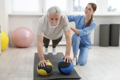 Photo of Doctor and patient exercising with medicine ball in clinic