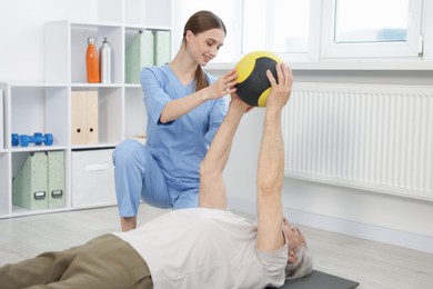 Photo of Doctor and patient exercising with medicine ball in clinic