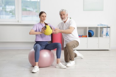 Photo of Doctor and patient exercising with medicine ball in clinic