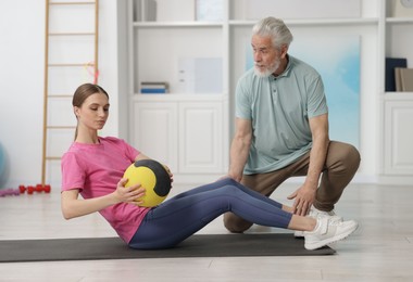 Photo of Doctor and patient exercising with medicine ball in clinic