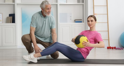 Photo of Doctor and patient exercising with medicine ball in clinic