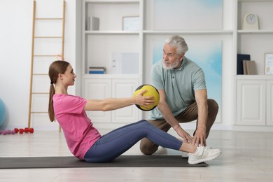Photo of Doctor and patient exercising with medicine ball in clinic