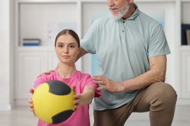 Photo of Doctor and patient exercising with medicine ball in clinic