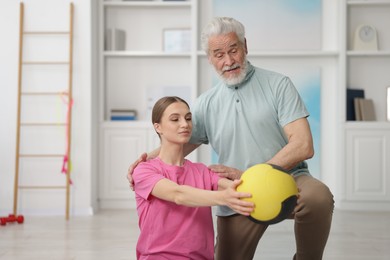 Photo of Doctor and patient exercising with medicine ball in clinic