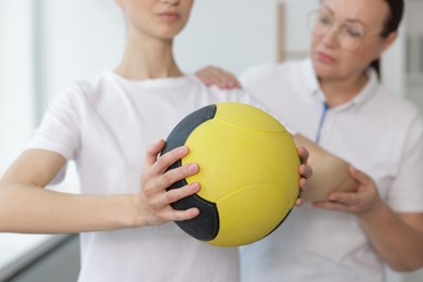 Photo of Doctor and patient exercising with medicine ball in clinic, selective focus