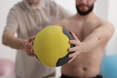 Photo of Doctor and patient exercising with medicine ball in clinic, closeup