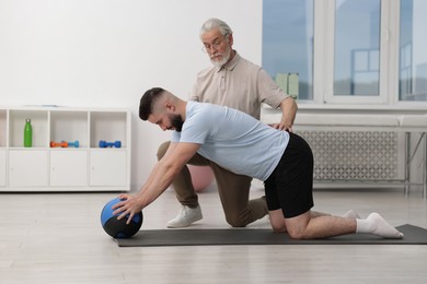 Photo of Doctor and patient exercising with medicine ball in clinic