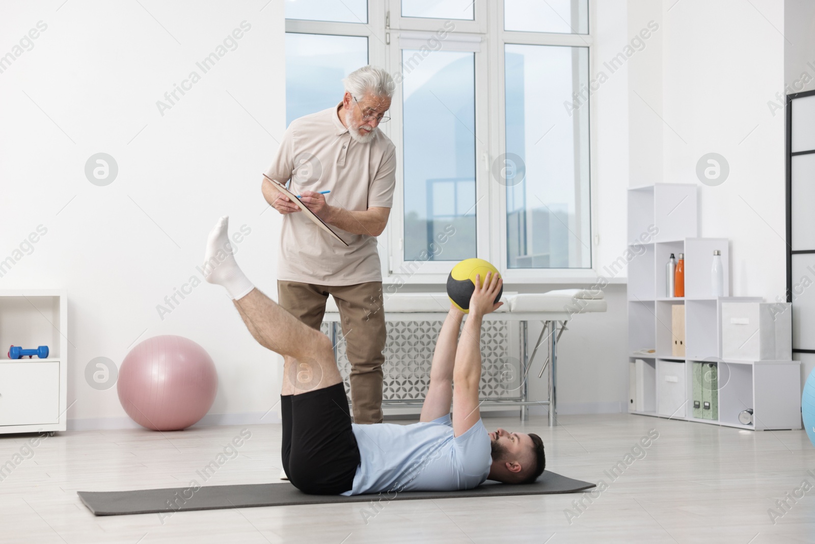 Doctor and patient exercising with medicine ball in clinic Photo of Doctor and patient exercising with medicine ball in clinic