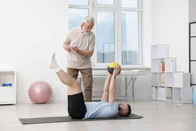 Photo of Doctor and patient exercising with medicine ball in clinic