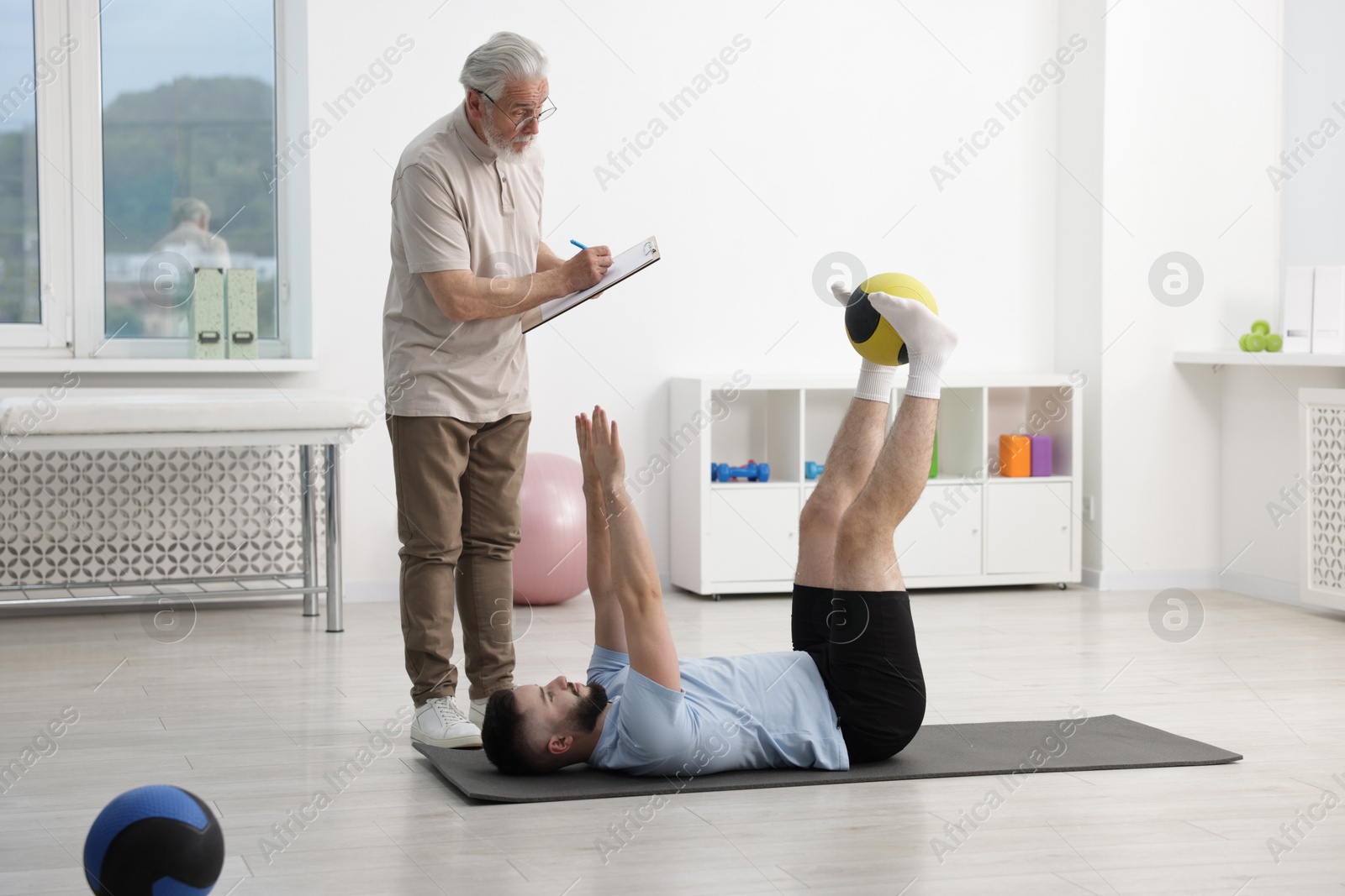 Doctor and patient exercising with medicine ball in clinic Photo of Doctor and patient exercising with medicine ball in clinic