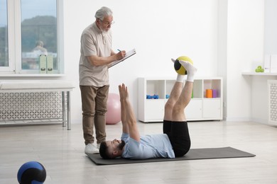 Photo of Doctor and patient exercising with medicine ball in clinic