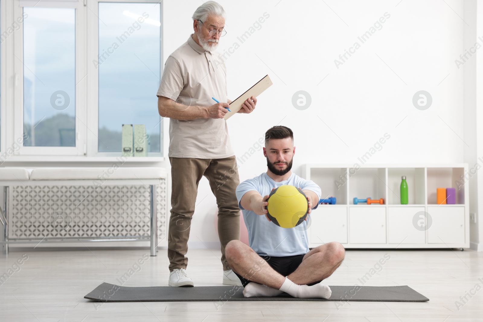 Doctor and patient exercising with medicine ball in clinic Photo of Doctor and patient exercising with medicine ball in clinic