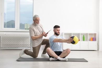 Photo of Doctor and patient exercising with medicine ball in clinic