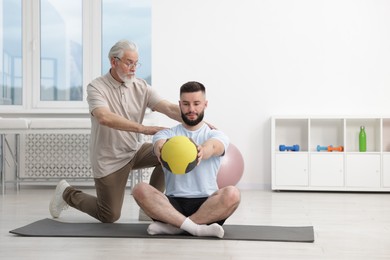 Photo of Doctor and patient exercising with medicine ball in clinic
