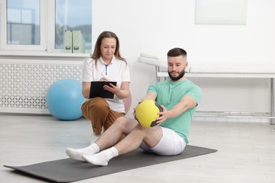 Photo of Doctor and patient exercising with medicine ball in clinic