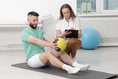 Photo of Doctor and patient exercising with medicine ball in clinic