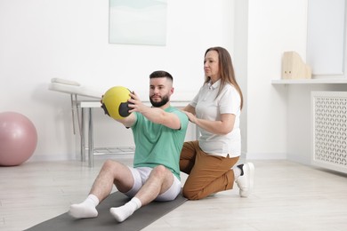 Photo of Doctor and patient exercising with medicine ball in clinic