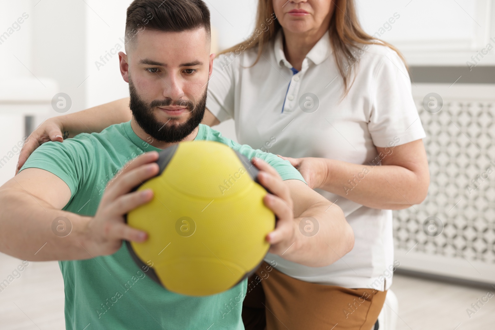 Photo of Doctor and patient exercising with medicine ball in clinic