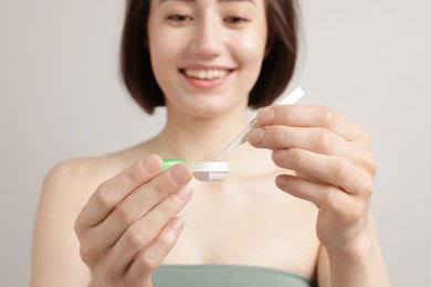 Photo of Woman taking contact lens out of case on light background, selective focus
