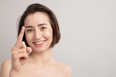 Photo of Woman with contact lens on light background. Space for text