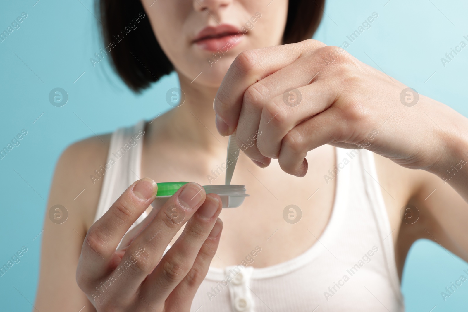 Woman taking contact lens out of case on light blue background, closeup Photo of Woman taking contact lens out of case on light blue background, closeup
