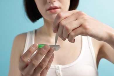 Photo of Woman taking contact lens out of case on light blue background, closeup