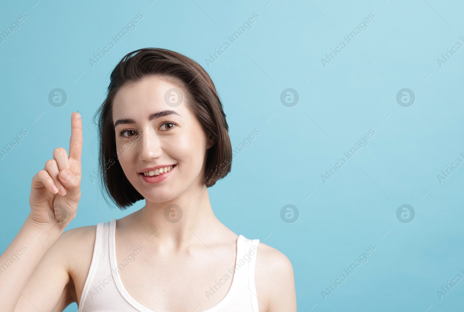 Photo of Woman with contact lens on light blue background. Space for text