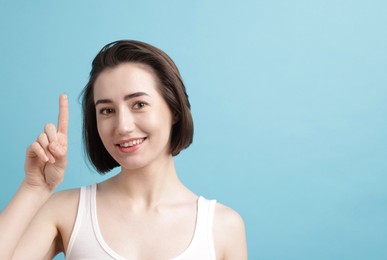 Photo of Woman with contact lens on light blue background. Space for text