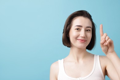 Photo of Woman with contact lens on light blue background. Space for text