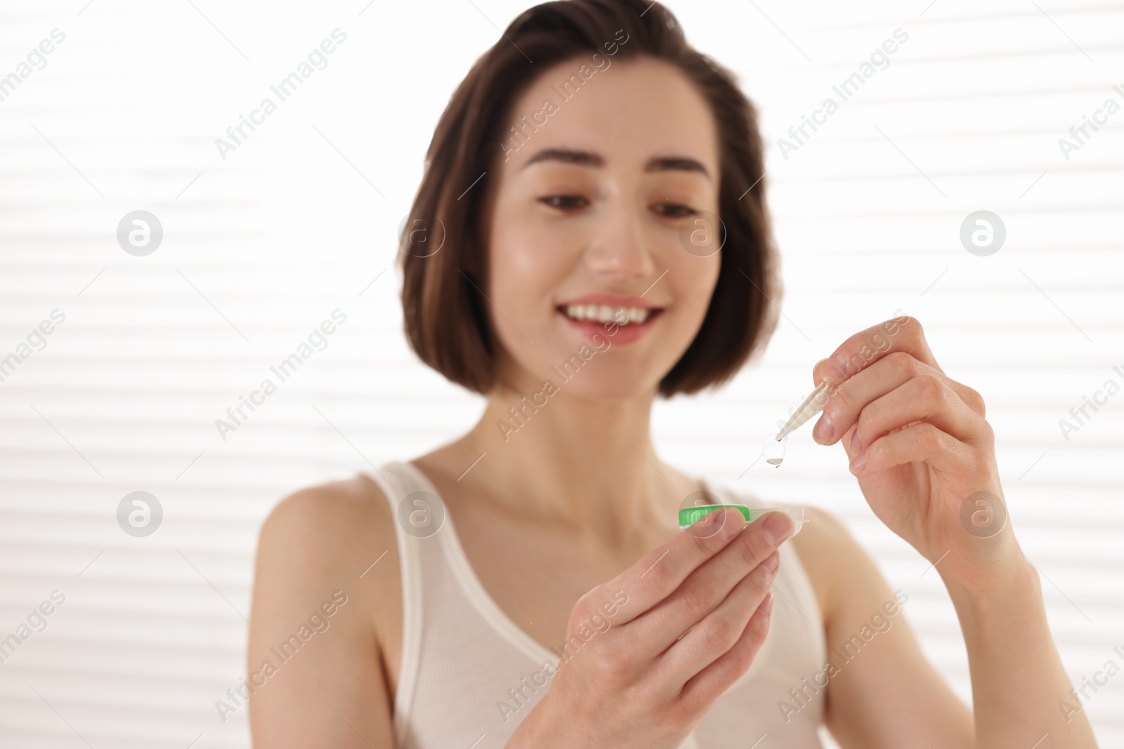 Photo of Woman taking contact lens out of case indoors