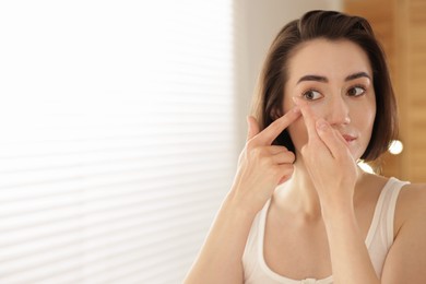 Photo of Beautiful woman putting in contact lens indoors. Space for text