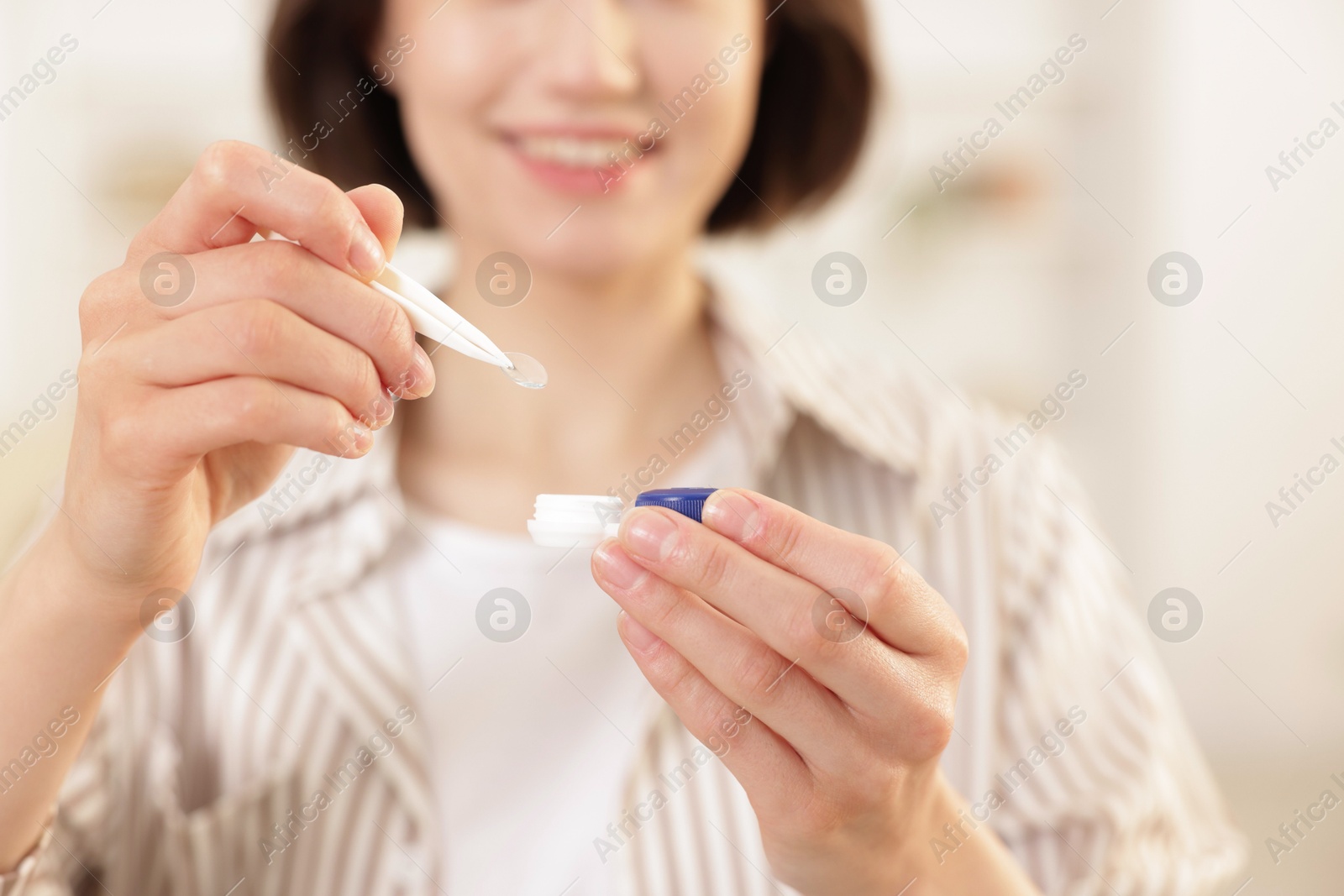 Woman taking contact lens out of case indoors, closeup Photo of Woman taking contact lens out of case indoors, closeup