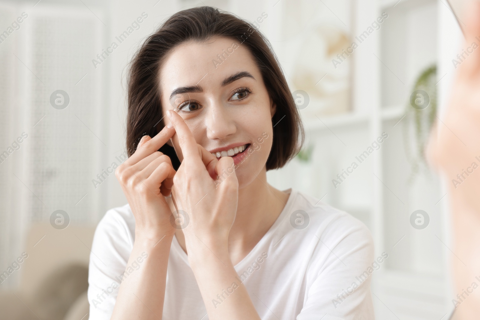 Beautiful woman putting in contact lens indoors Photo of Beautiful woman putting in contact lens indoors